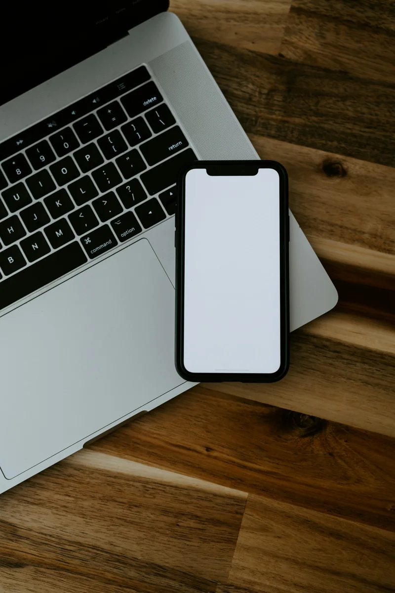 Laptop and phone resting on a wooden desk